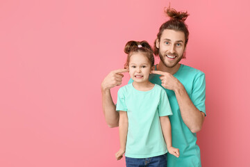 Funny man and her little daughter on pink background. April fools' day celebration