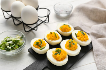 Board and holder with eggs on white wooden background. Easter celebration