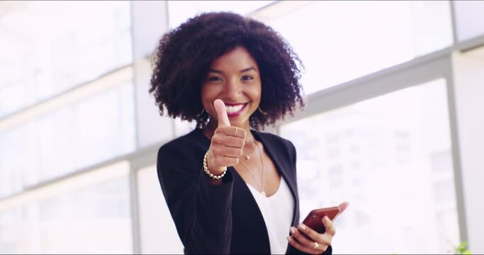 Portrait of a happy young business woman of african ethnicity employee worker looking at camera showing thumbs up gesture in her company office. Happy young woman with an afro being successful at work