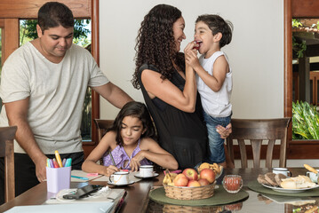 Mãe e pai com crianças comendo e fazendo dever de casa
