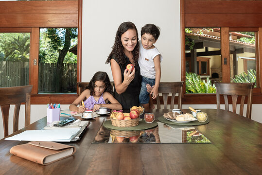 M&atilde;e com crian&ccedil;as comendo e fazendo dever de casa