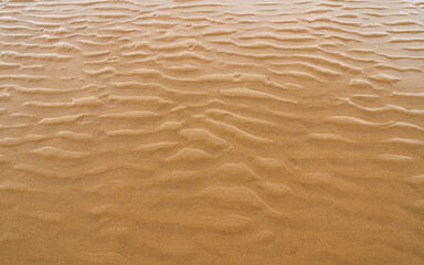 Detail of sand with water and small dunes on the beach 