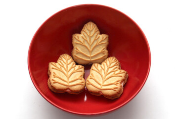 Delicious cookies filled with vanilla cream made with honey or maple syrup from Canadian trees, the traditional sweet of Canada in a red bowl of heart shape
