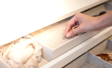 Female hand choosing the ring from the jewelry box that is decorated in the built-in wardrobeobe in the bedroom,