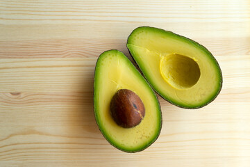 Avocado on wooden background. Avocado fruit. Raw healthy green food. Whole and half avocado.