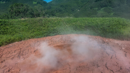 The hot spring is a clay pot. Close-up. The edges of the cauldron are cracked. Steam over the...