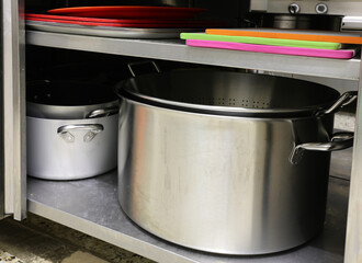stainless steel pot and other cookware and cutting boards inside an industrial kitchen