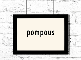 Black frame hanging on white brick wall with inscription pompous