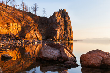 Fototapeta na wymiar Baikal Lake on May evening. Beautiful rocks of Olkhon Island near the village of Khuzhir are illuminated by the warm light of the setting sun. Natural background. Spring travel and outdoor recreation