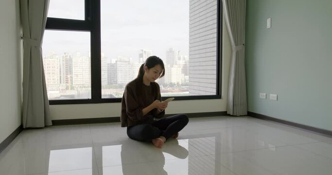 Woman use mobile phone and sit on the floor at home