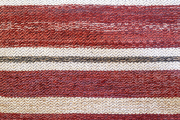 Fototapeta premium Traditional woven rug shades of red motley. rustic mat