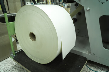 A roller of white printing paper on a trolley in a printing house. Paper for printing self-adhesive...