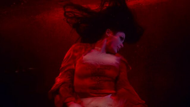 portrait of a brunette with long hair in dark water. red light. the middle plan