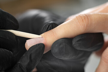 female manicure process. unrecognizable lady doing manicure in spa salon. female beauty and health. The master forms the shape of the cuticles using a bamboo stick - obrazy, fototapety, plakaty