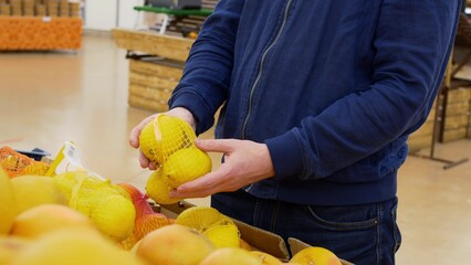 A man holds lemons and ginger in his hands, buying lemon and ginger in a store, a man chooses vegetables in the market for the preparation of medicinal products from simple at home.