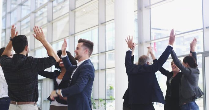 Cheerful diverse group of business people high fiving and celebrating positively corporate success. Happy workers being carefree after achieving workplace victory
