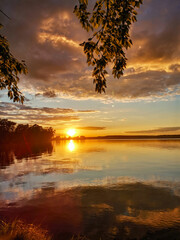 Sunset on a pond with blue sky, red clouds and water with reflection. Russia.