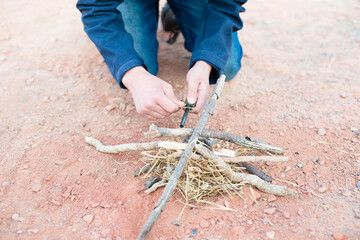 Starting a fire with a firesteel, survival and adventure equipment, outdoor skill, man making a...