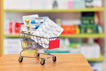 Shopping cart filled with blister packs of medicine on pharmacy drugstore shelves background....