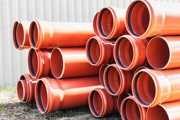 Orange sewer pipes at the construction site. Preparation for the installation of an underground...