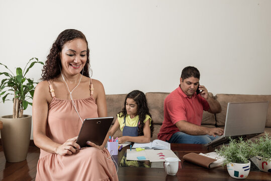 Casal brasileiro trabalhando com filha na sala de estar