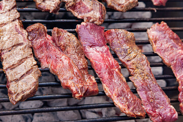 Raw beef meat is grilled, close-up. Beef steaks on a grill grid.