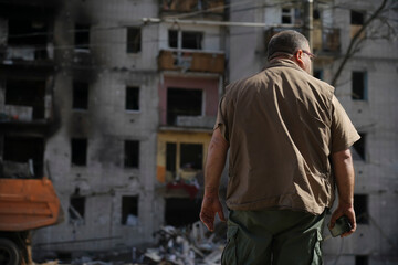 A man looks at a destroyed house that was hit by a shell