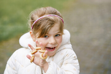 Beautiful little child girl eats bred bagels called sushki. Preschool child and healthy snack
