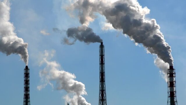 Factory chimneys smoke into the sky. Industrial pipes pollute the ozone layer.