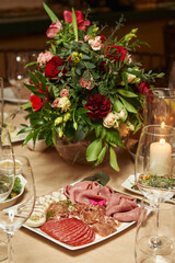 meat cuts on a festive table decorated with red flowers