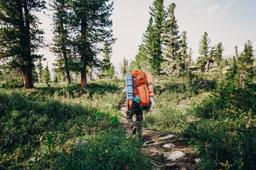 Man hiker on summer day and with big heavy hiking backpack full of travel staff. Travel Lifestyle...