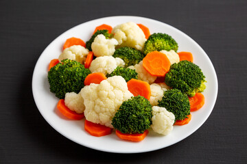 Mixed Organic Steamed Vegetables (Carrots, Broccoli and Cauliflower) on a Plate on a black...