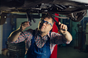 Obraz na płótnie Canvas Portrait Shot of a Handsome Mechanic Working on a Vehicle in a Car Service.