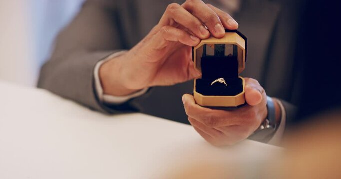 I should've done this ages ago. A man proposing in a restaurant. Unrecognizable man posing with jewellery. Closeup of a proposal. 