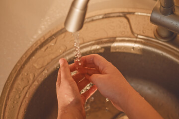 The child washes his hands. Water flows from a tap. Cleanliness is the key to health.