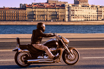 A man rides a bike along the embankment. The motorcyclist travels. A male rides around the city on...