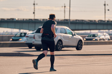 A man runs along the road next to the cars. Sports activities in the fresh air.