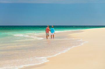 Loving senior couple walking on white sandy beach