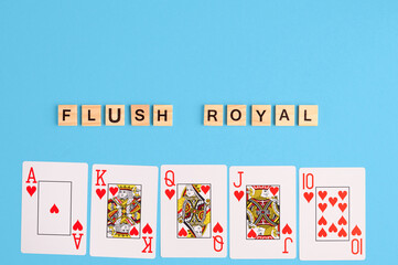 Flush royal combination. Poker Playing Cards on blue background with wooden blocks. Flatlay, copy space, concept