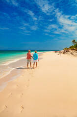Loving retired couple walking on beach leaving footprints