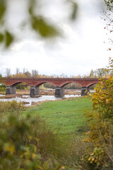 Autumn weather view of old red brick over Venta river in small countryside city Kuldiga, Latvia.