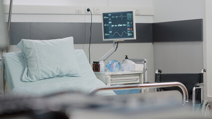 Nobody in hospital ward with heart rate monitor and bed for healthcare treatment and recovery. Empty emergency room for intensive care and reanimation with medical equipment and medicine