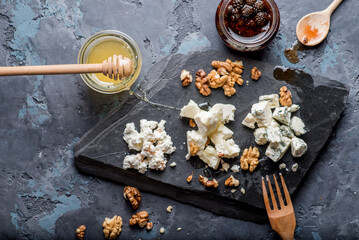 various cheeses on a plate with sauces and.confitures, honey and nuts