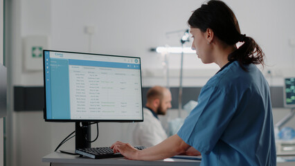 Close up of woman nurse working on computer in hospital ward. Medical assistant typing on keyboard...