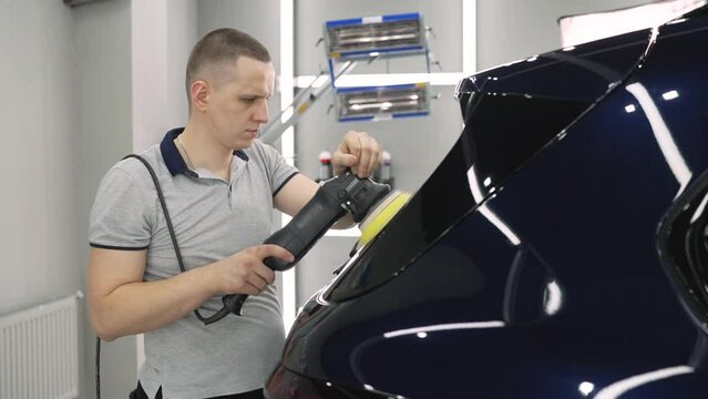 Vehicle detailing. A young man polishing his car. Master detailing center polishes a car body. The master polishes the car.