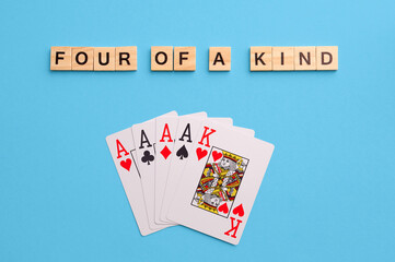 Four of a kind combination. Poker Playing Cards on blue background with wooden blocks. Flatlay, copy space, concept
