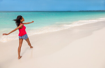 Fototapeta na wymiar Afro American girl walking barefoot by tropical ocean