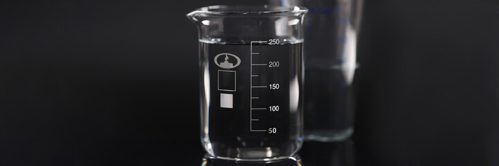 Closeup of chemical beaker with water on black background