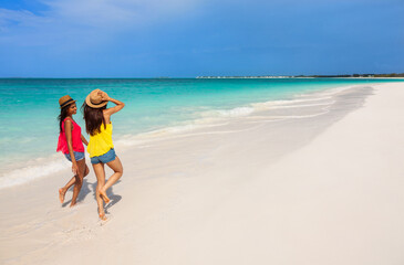 Fototapeta na wymiar Girls wearing Panama hats skipping by tropical ocean