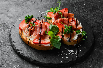 Sandwich with cheese, prosciutto, strawberries and basil. Bruschetta. Top view. On a stone...
